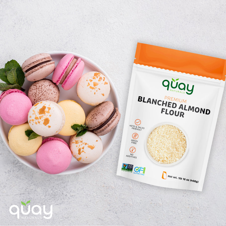 A plate of colorful macarons with mint leaves next to a bag of Quay Naturals Premium Blanched Almond Flour.