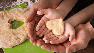 Hands holding heart-shaped dough