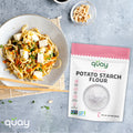 A dish of noodles with tofu and vegetables is paired with peanuts in bowl a bag of Quay Naturals Premium Potato Starch Flour.